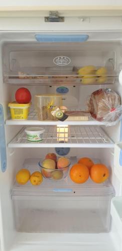um frigorífico aberto com laranjas e outras frutas em Athena and The Owl Beachside Apt em Pafos