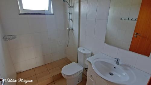 a white bathroom with a toilet and a sink at Turismo Rural- Casas de Campo - Eco & Nature - Monte Horizonte in Santiago do Cacém