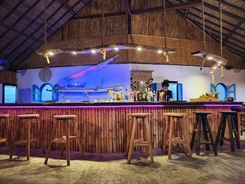吉利阿尔Formosa Beach Club & Bungalow的一间酒吧,里面设有木凳,还有一间有船的房间