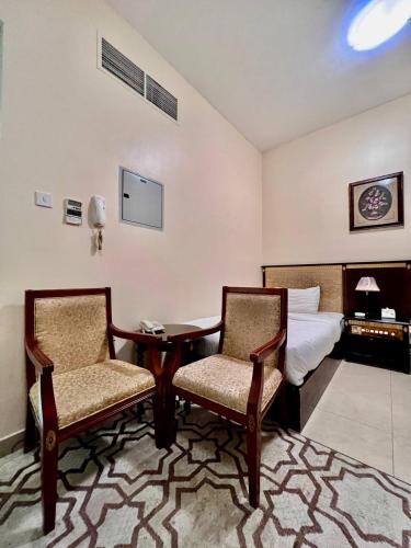 a hotel room with a bed and two chairs and a table at Dream Palace Hotel in Ajman 