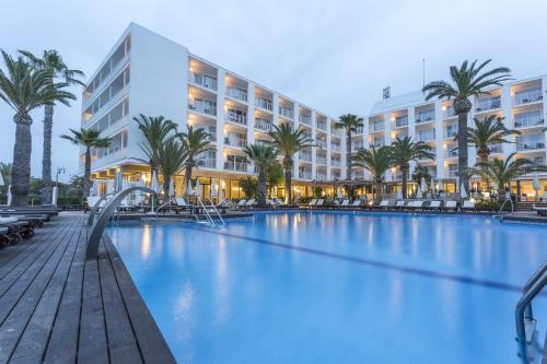 einen Pool mit Palmen und ein Hotel in der Unterkunft Palladium Hotel Palmyra - Adults Only in Sant Antoni de Portmany