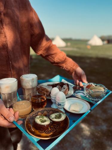 a man holding a tray of food on a table at Bygagergaard in Askeby