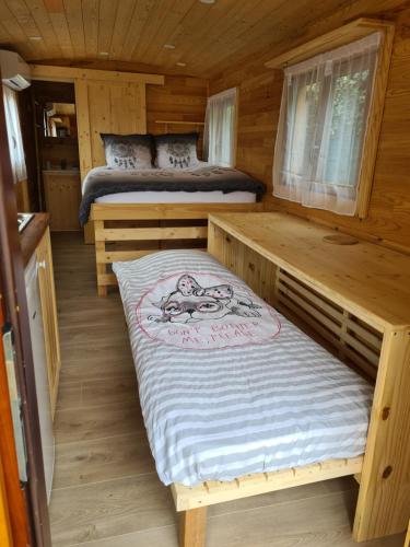 a bedroom with two beds in a wooden cabin at Tiny House Roulotte in Cuges-les-Pins
