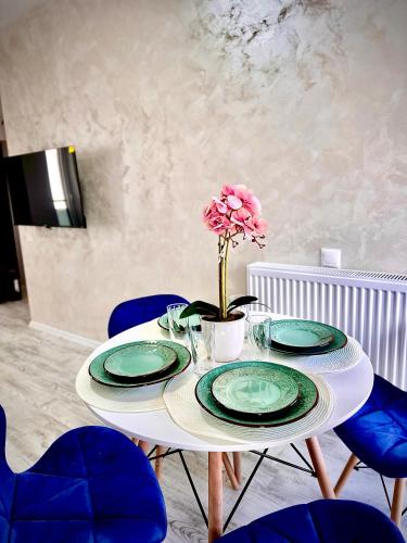 uma mesa com pratos e um vaso com uma flor em Vik’s Apartament Sunrise Residence em Mangalia