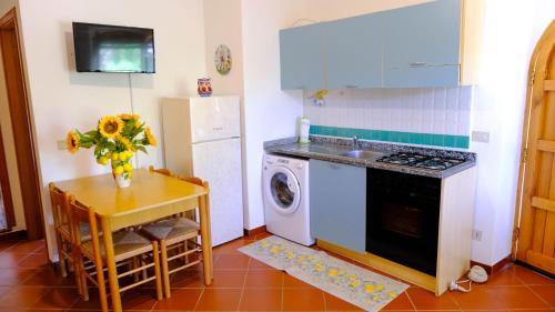 cocina con nevera, mesa y lavadora en La Casa dei due Ulivi, en Capo dʼOrlando