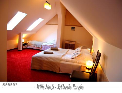 シュクラルスカ・ポレンバにあるWilla Nimfa -Również na wyłączność dla Grup nocleg z wyżywieniemのベッドルーム(ベッド2台付)が備わる屋根裏部屋です。