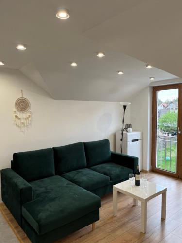 a living room with a green couch and a table at Apartament Comfort w Kujankach nad jeziorem in Kujanki