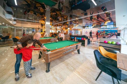 a man and a boy playing pool in a store at Aquapark Health Resort & Medical SPA Panorama Morska All Inclusive in Jarosławiec