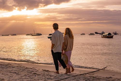 a couple standing on the beach watching the sunset at The Neela Boutique Hotel Stone Town in Zanzibar City