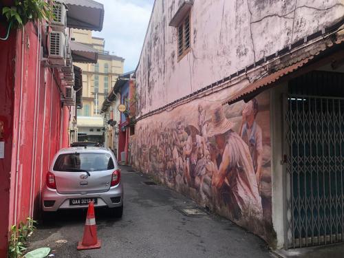 Un coche estacionado junto a una pared con una pintura. en 24 Seven B&B Mamasan, en Kuching