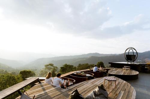 a group of people sitting at tables on a roof at JADAE HOUSE Doichang in Ban Huai Khai