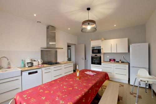 d'une cuisine avec des placards blancs et une table rouge. dans l'établissement La grande maison de Suzanne et son Jardin, à Albi