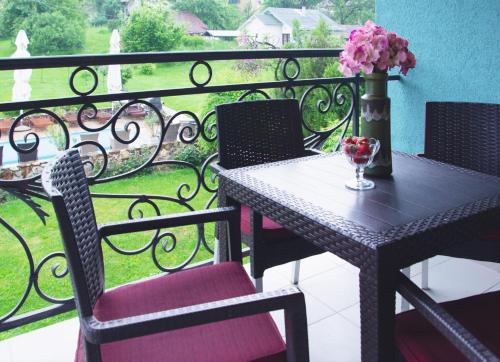 a table with chairs and a vase of flowers on a balcony at Vila Ljubica in Vrnjačka Banja