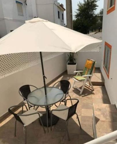 una mesa y sillas con una sombrilla en el patio en Casa Rosylu, en Ferragudo