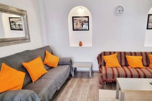 sala de estar con sofá gris y almohadas de color naranja en Casa Rosylu, en Ferragudo