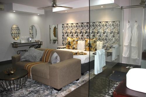 a bedroom with a bed and a couch in a room at Ecolux Boutique Hotel in Komatipoort