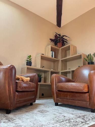 2 sillas de cuero marrón en una sala de estar con estanterías en Appartement de charme 80m2, en Givors