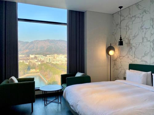 a hotel room with a bed and a large window at Hotel Avenue in Changwon