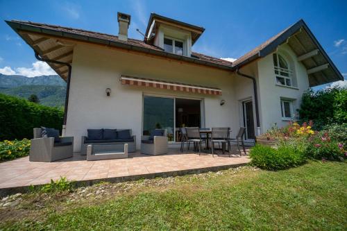 uma casa com um pátio com uma mesa e cadeiras em Entre lac et montagnes em Doussard