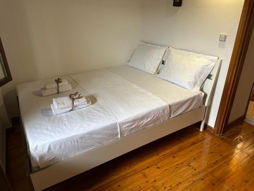 a bed with white sheets and two towels on it at Elena maisonette by the sea in Kamena Vourla