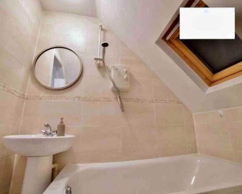 ein Badezimmer mit einem Waschbecken, einer Badewanne und einem Spiegel in der Unterkunft Charming Studio in Golders Green in London