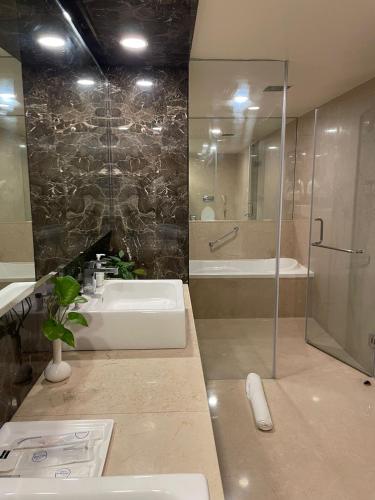 a bathroom with a sink and a shower and a tub at Paradigm Sarovar Portico in Kākināda