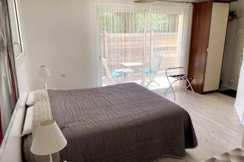 ein Schlafzimmer mit einem Bett und einen Balkon mit einem Tisch und Stühlen in der Unterkunft Studio indépendant 3 étoiles dans magnifique villa au bord du lac d'Annecy in Veyrier-du-Lac