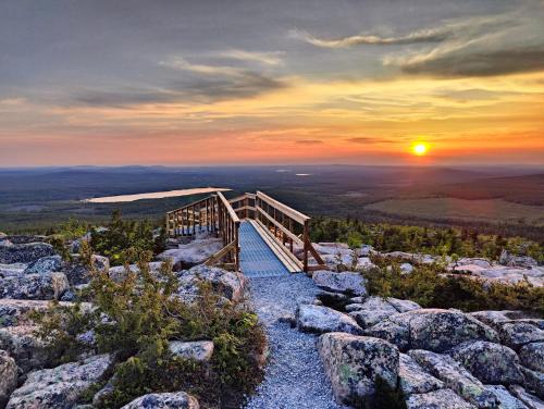 a boardwalk on top of a mountain at sunset at Isokelo Log Apartments in Salla