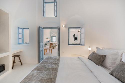 a white bedroom with a bed and a mirror at Villa Paradeisos Karterados in Karterados