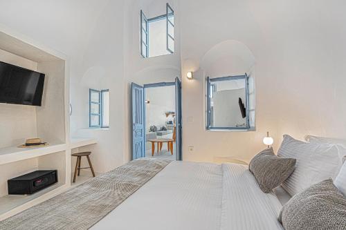 a white bedroom with a bed and a desk at Villa Paradeisos Karterados in Karterados