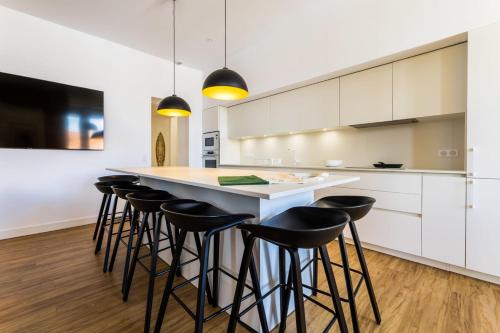 une cuisine avec des placards blancs et un bar avec des tabourets dans l'établissement MARIPOSA KEYWEEK Loft Biarritz, à Biarritz