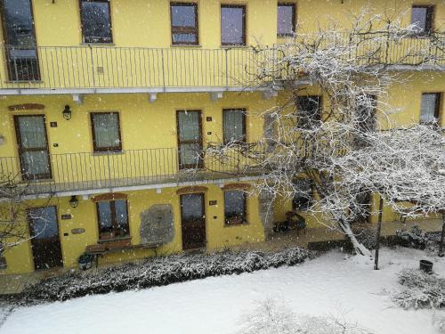 a yellow building with snow on the ground at Agriturismo Tra Serra E Lago in Roppolo