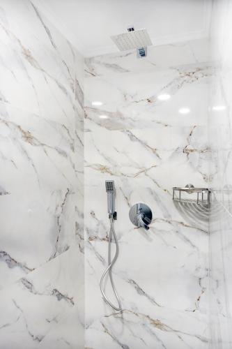 a bathroom with white marble walls and a shower at Okean Apartments in Ierissos