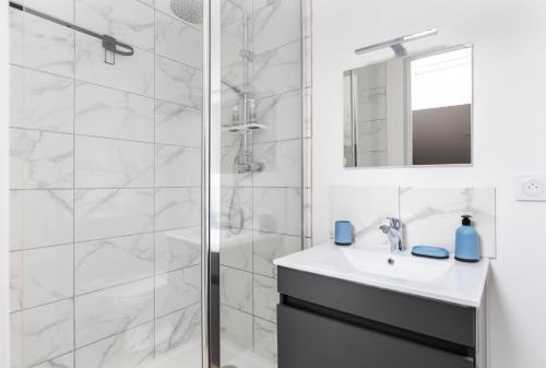 une salle de bain blanche avec une douche et un lavabo dans l'établissement Gambetta402 CahorsCityStay, à Cahors