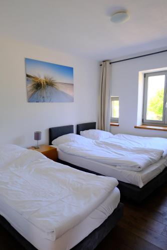 two beds in a room with white sheets at Kutscherhaus Thorstorf in Warnow