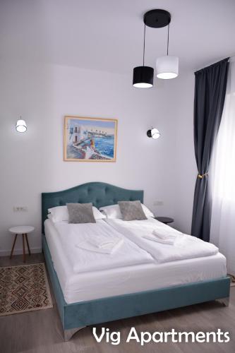 a bedroom with a large bed with a blue headboard at Vig Apartments in Timişoara