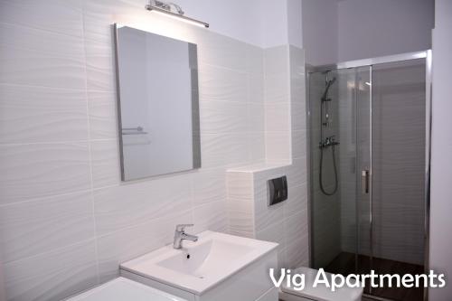 a white bathroom with a sink and a shower at Vig Apartments in Timişoara