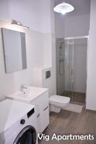 a white bathroom with a sink and a washing machine at Vig Apartments in Timişoara