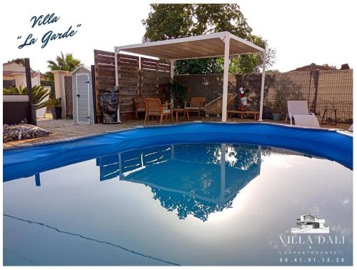 een blauw zwembad met een tafel en een paviljoen bij Villa DALI LA GARDE 260m2 Jacuzzi, Sauna, Piscine, jardin 500m2, 5 minutes de la Plage in La Garde