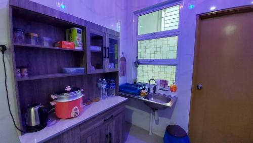 cocina púrpura con fregadero y ventana en 42 Avenue Homestay Samarahan en Kota Samarahan