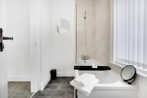 ein weißes Bad mit einer Badewanne und einem Spiegel in der Unterkunft Stunning 4-Bedroom, 2 Bathrooms in Sunderland in Sunderland