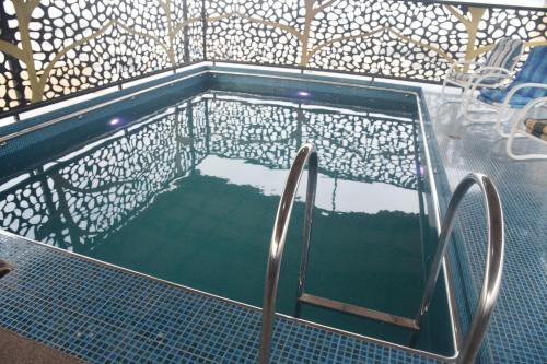 a swimming pool with a reflection in the water at The Rich Hotel & Apartments in Lahore