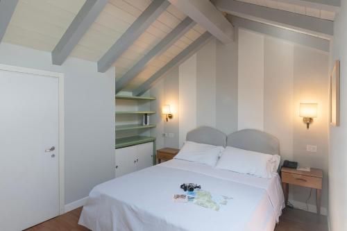 1 dormitorio con cama blanca y suelo de madera en Hotel Beau Rivage, en Baveno