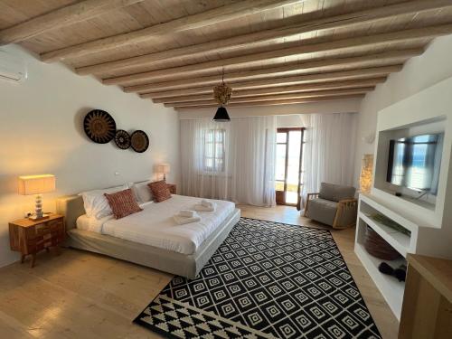 een slaapkamer met een bed en een tv en een bank bij ONE-VILLAS Cosset Villa BohoChic Sea&HarbourView and Sunset in Ornos