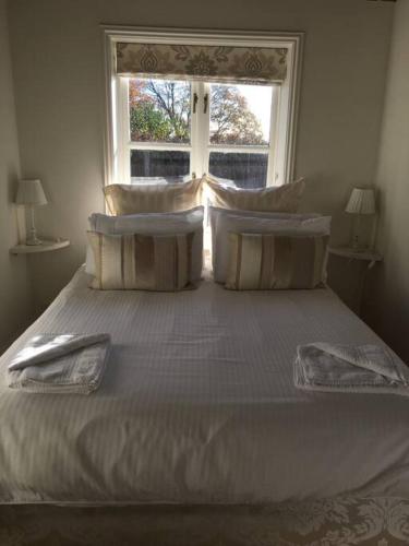 a white bed with a window in a bedroom at Waters edge in Rolvenden