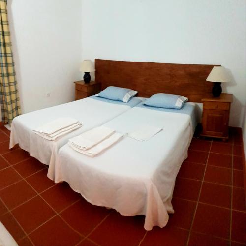 a bedroom with a large white bed with blue pillows at Casa da Avó Mirinha in Figueira e Barros