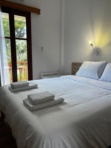 Una cama blanca con toallas y una ventana. en Sifnos Valley, en Faros