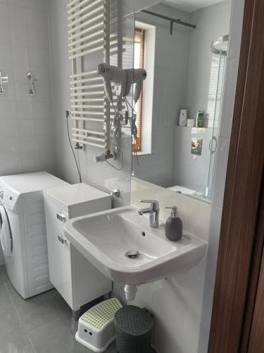 a white bathroom with a sink and a mirror at "Apartament pod Śnieżką" uroczy apartament z kominkiem in Karpacz