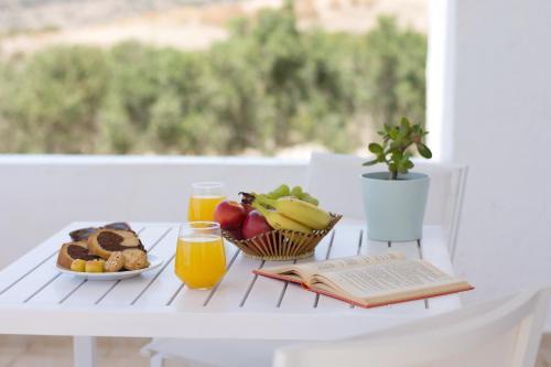 a table with a plate of fruit and juice and a book at Sarantis Suites & Apartments in Provatas
