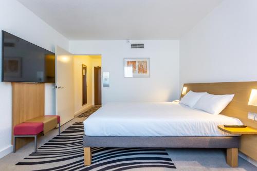 a hotel room with a bed and a tv at Novotel Bourges in Bourges